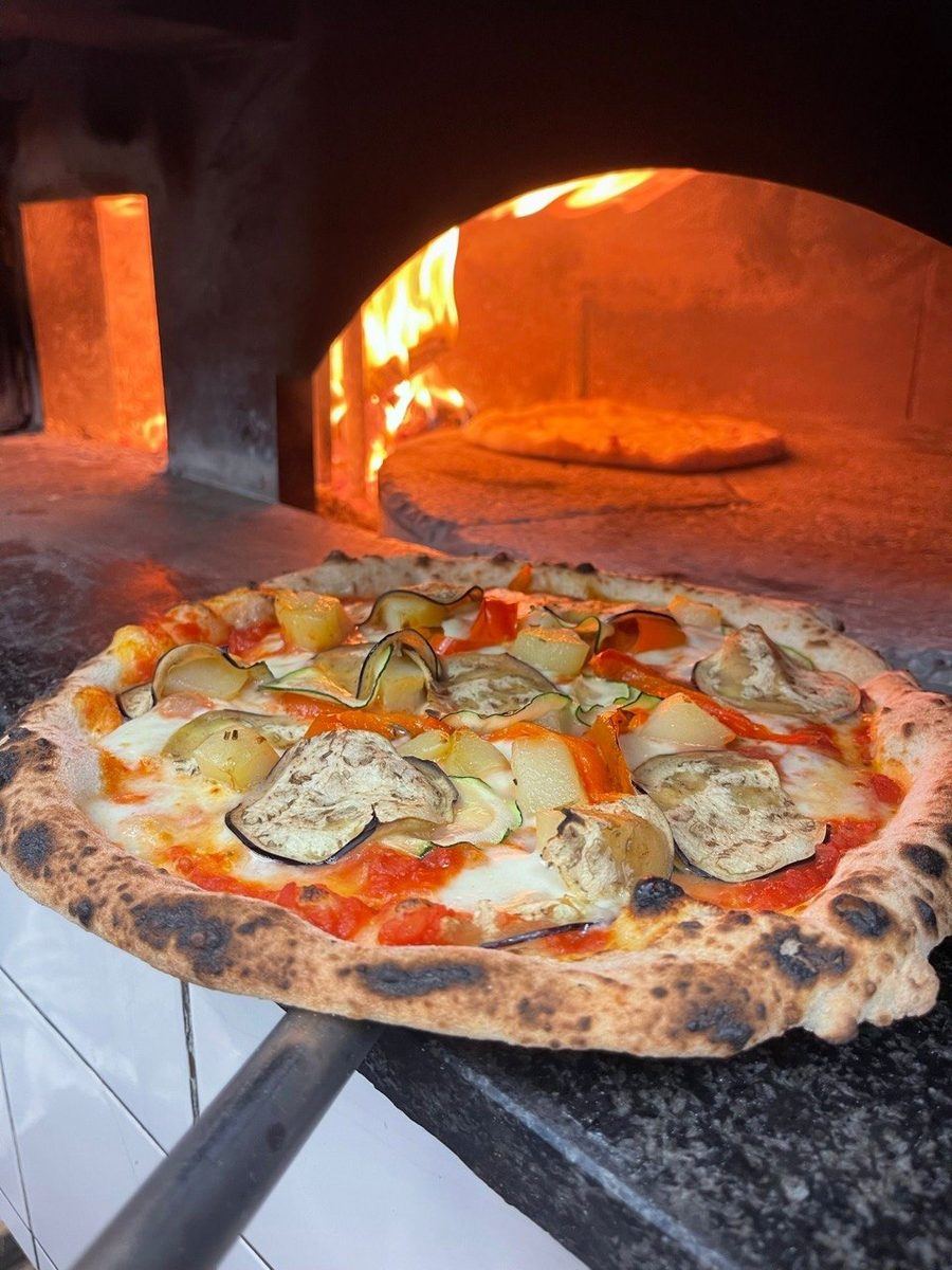 Pizza appena sfornata davanti al forno a legna
